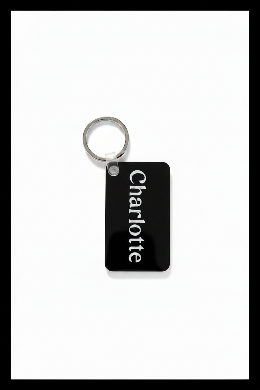 A black rectangular keychain tag with the name 'Charlotte' printed vertically in white, attached to a silver metal key ring on a white background with a black border.