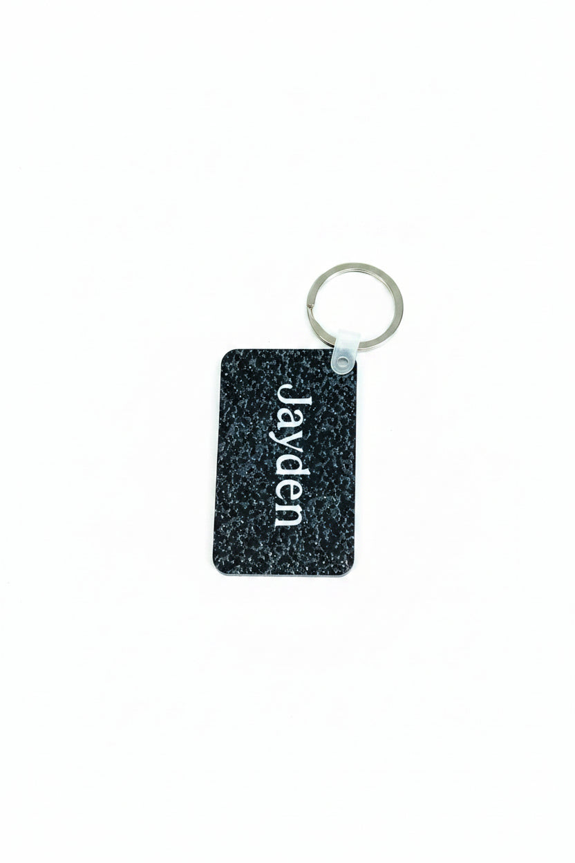 Personalized black speckle keychain with name Jayden in white. Roxzell