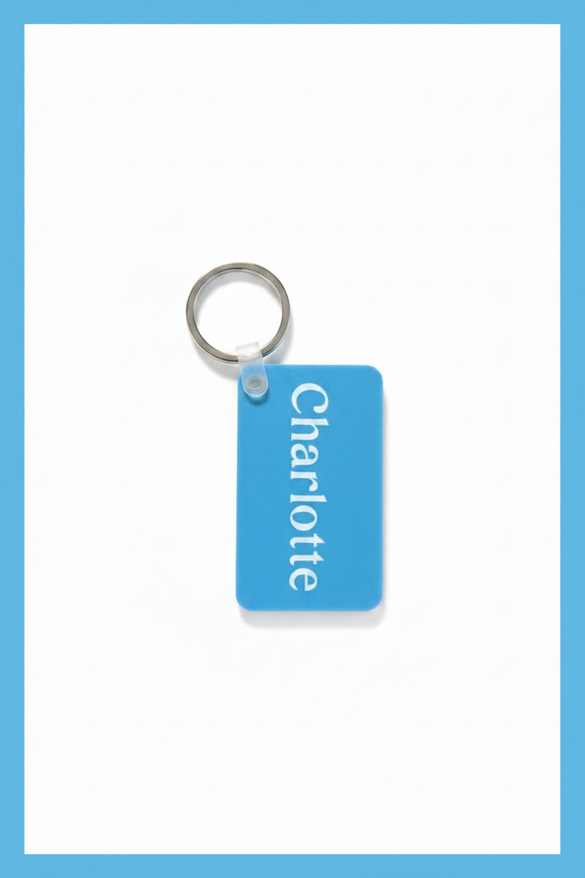 A light blue rectangular keychain tag with the name 'Charlotte' printed vertically in white, attached to a silver metal key ring on a white background with a light blue border.