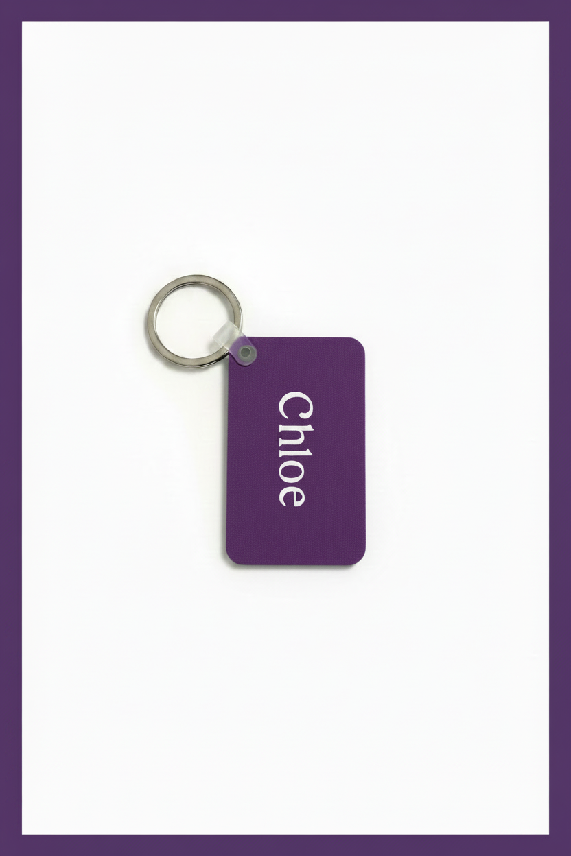 A purple personalized keychain with the name 'Chloé' printed in white, attached to a silver metal key ring, shown on a white background with a purple border. Roxzell