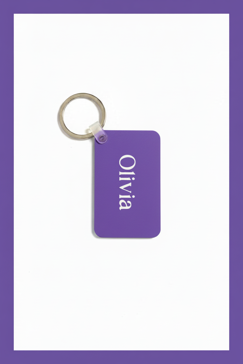 A rectangular purple keychain tag with rounded corners, featuring the name 'Olivia' printed vertically in white. The tag is attached to a silver metal split keychain against a plain white background with a purple border. Roxzell