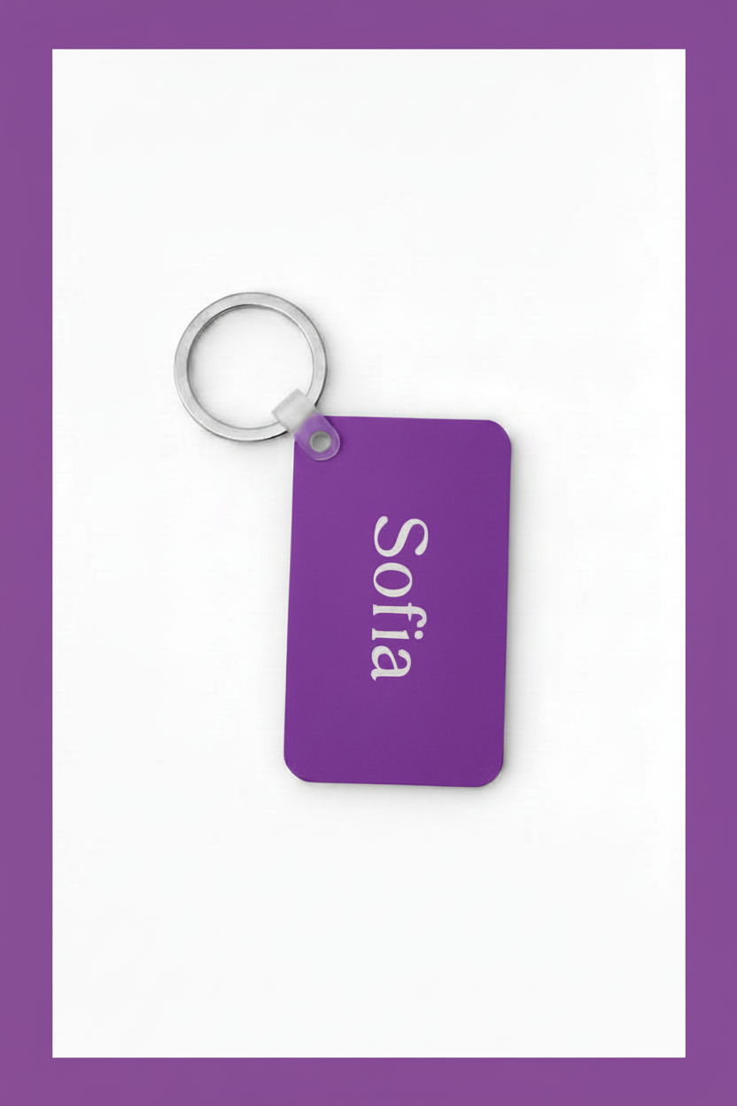 A rectangular purple keychain with rounded corners, attached to a silver metal ring. The tag is printed with the name 'Sofia' in white vertical text, set against a white background with a purple border. Roxzell