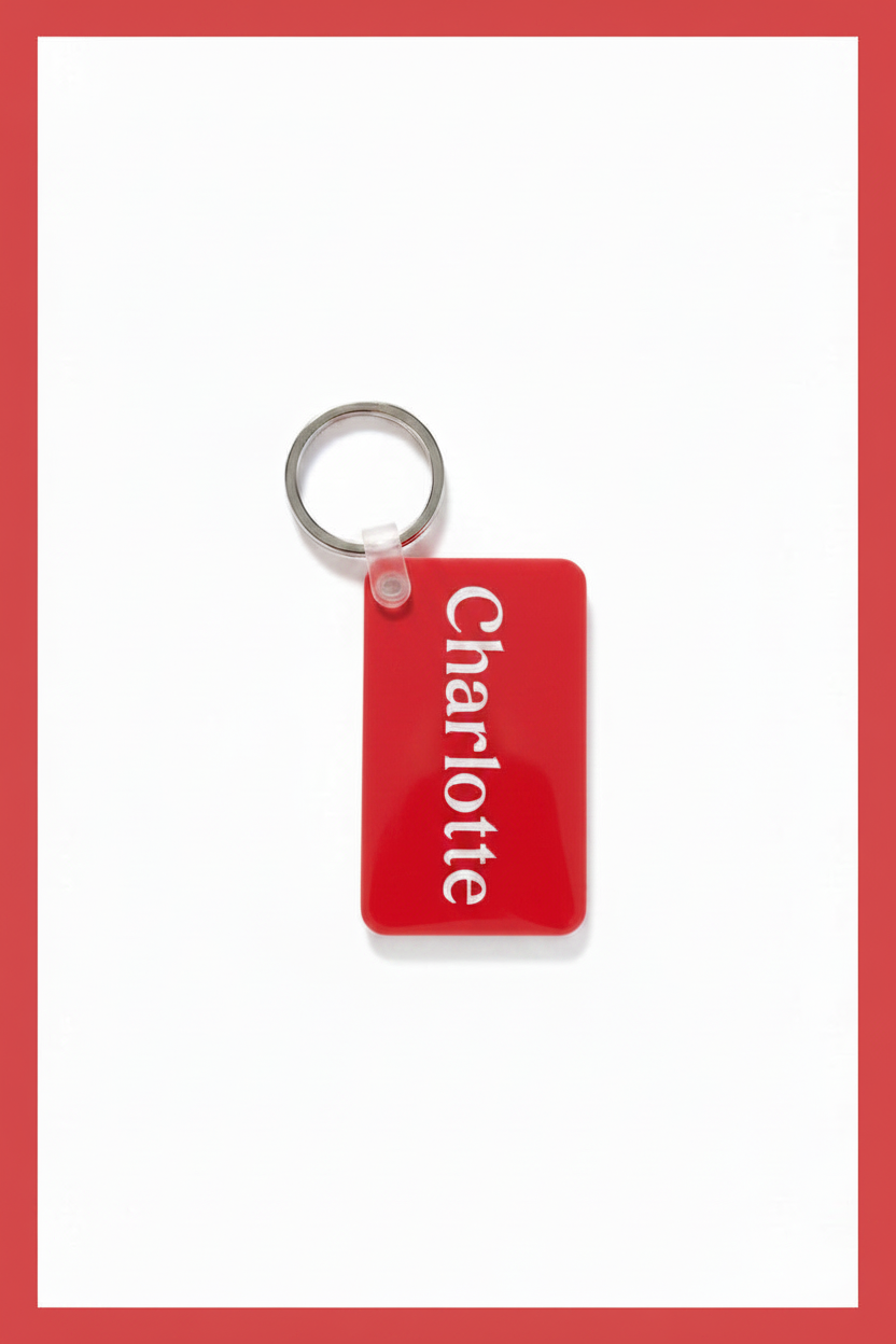 A red rectangular keychain tag with the name 'Charlotte' printed vertically in white, attached to a silver metal key ring on a white background with a light red border.