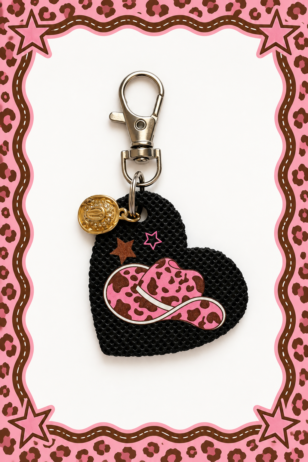 A heart-shaped black leather keychain charm featuring a pink and brown leopard-print cowboy hat, small pink and brown stars, and a gold-tone cowgirl hat charm, attached to a silver clasp. Roxzell