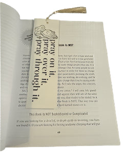 Book with a black and white bookmark featuring text 'pray on it, pray over it, pray through it.'