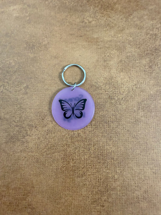 Purple acrylic butterfly keychain with "Spread Your Wings" on the reverse side.