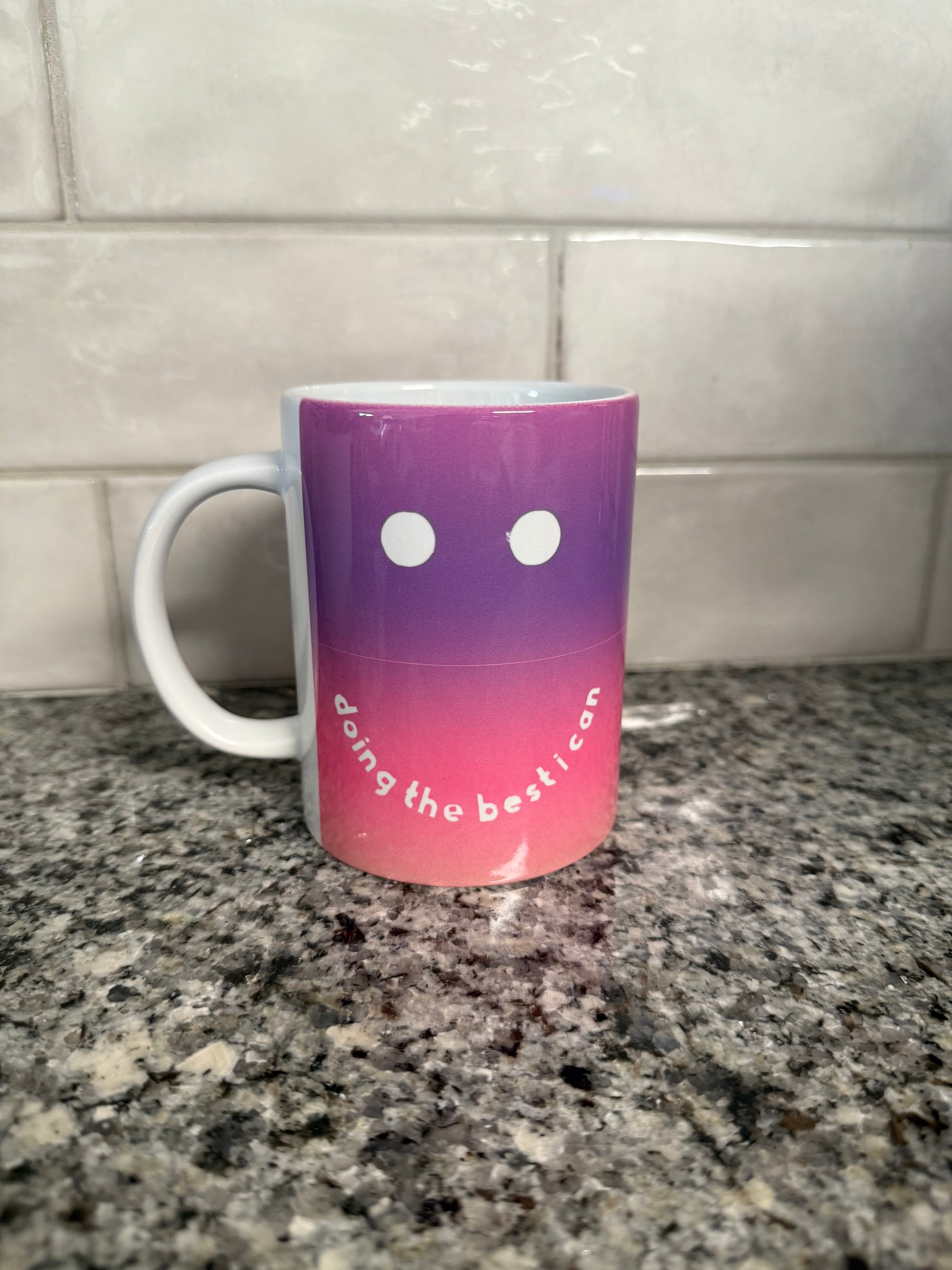 A purple and pink ceramic mug with a smiley face design and the phrase 'doing the best I can' written on it Roxzell