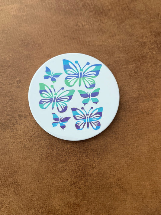 Round ceramic white coaster designed with blue and green butterflies.