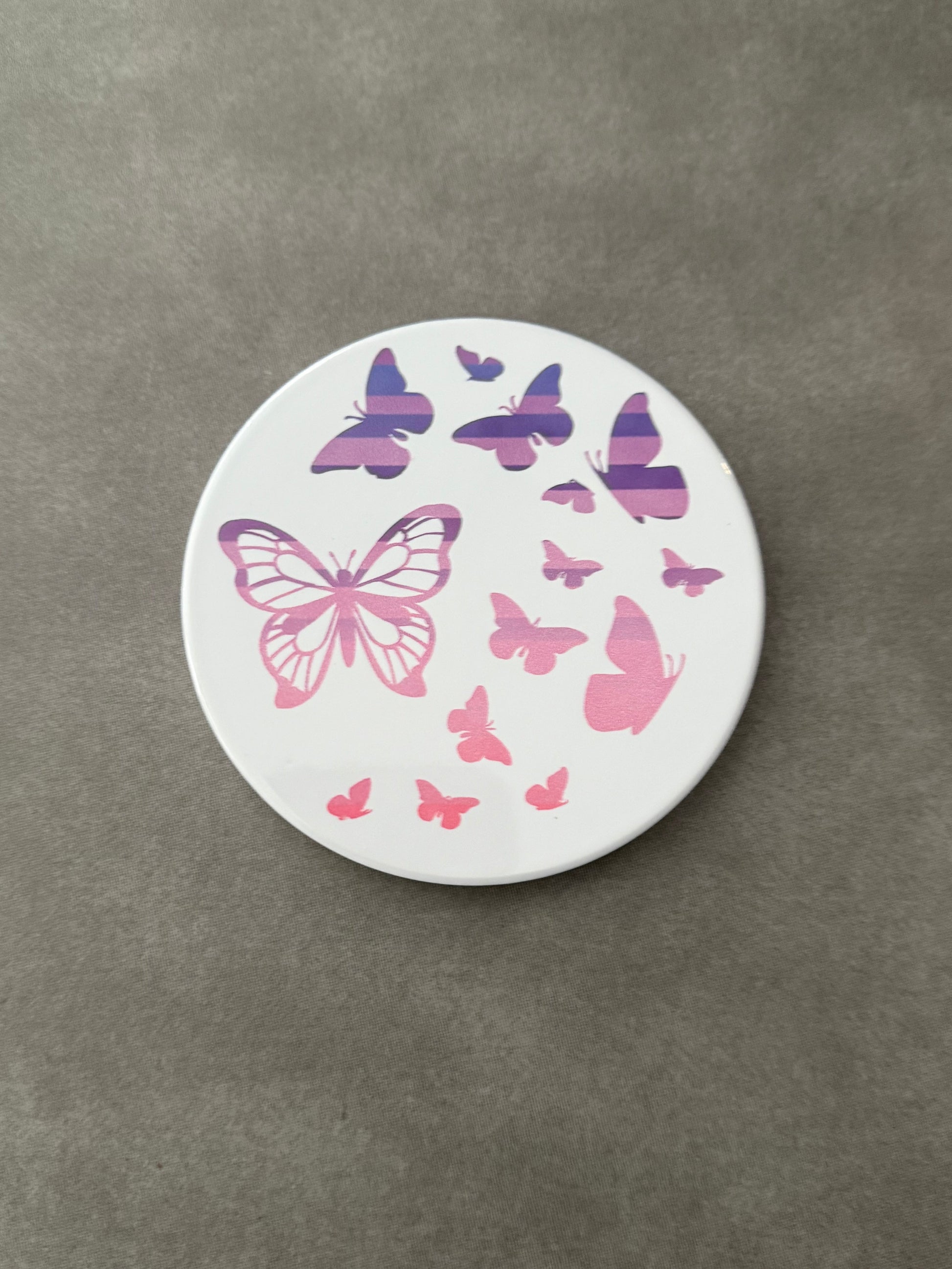 Round ceramic whit coaster designed with pink and purple butterflies.
