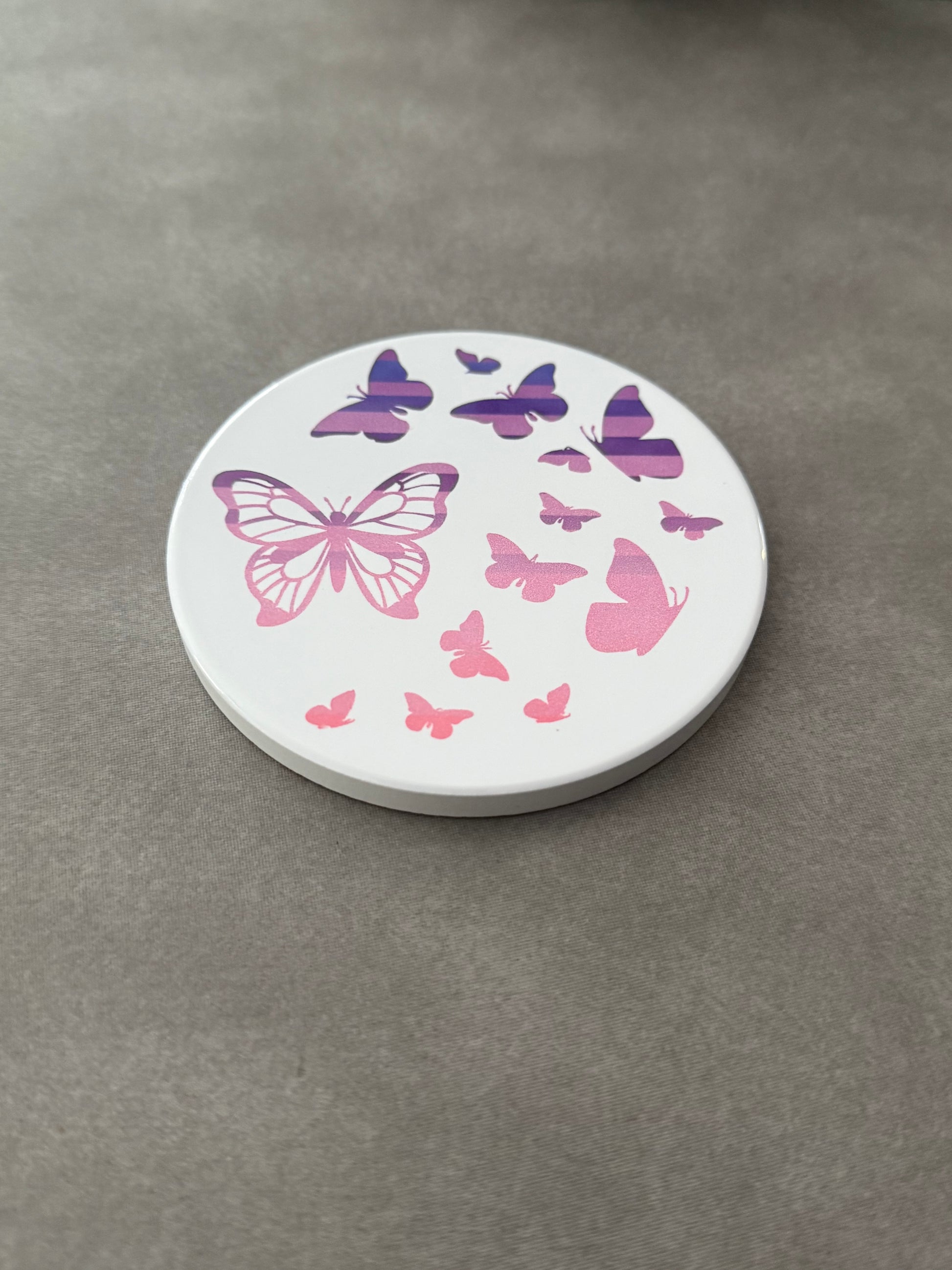Round ceramic whit coaster designed with pink and purple butterflies.