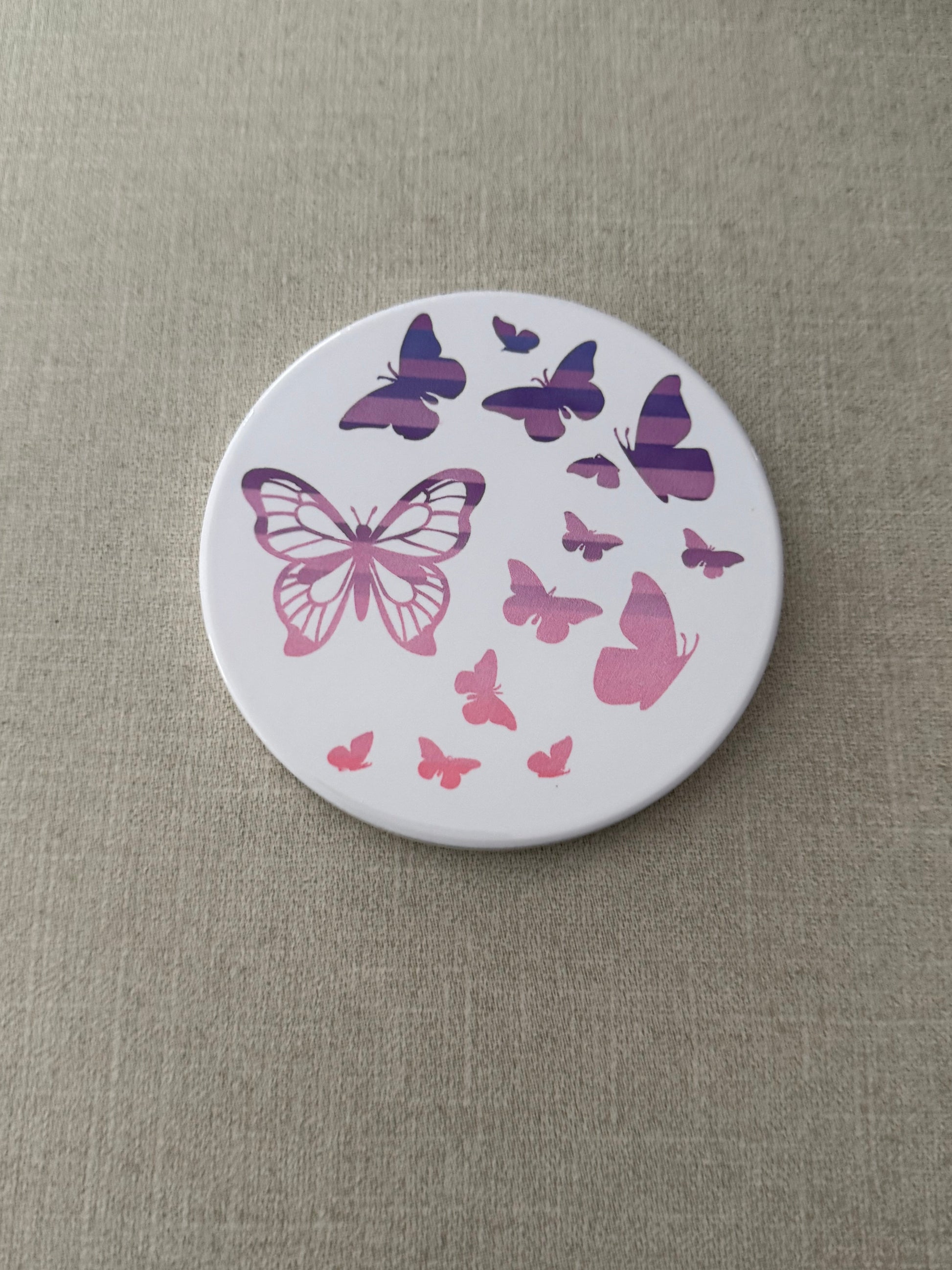 Round ceramic whit coaster designed with pink and purple butterflies.