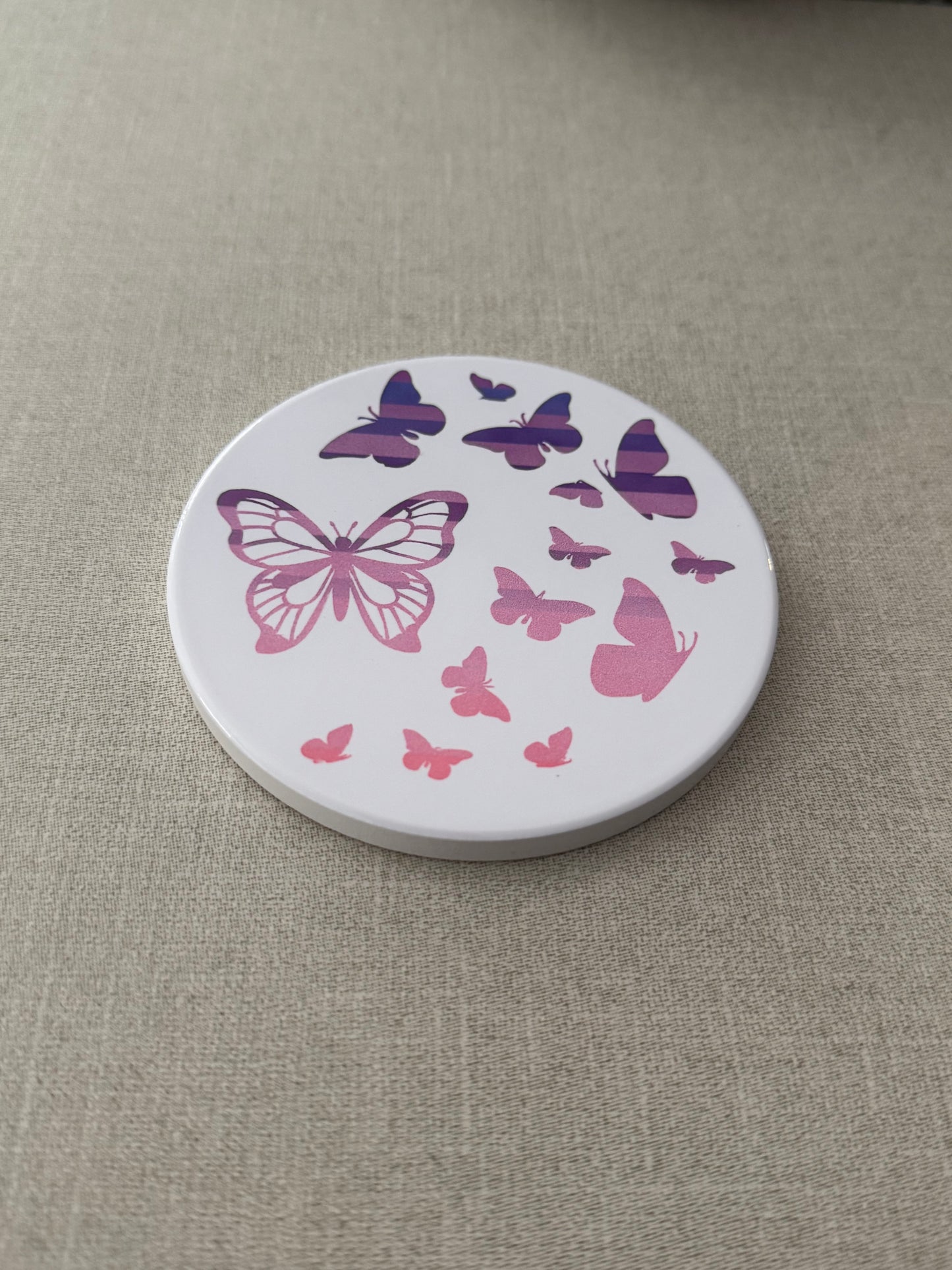 Round ceramic whit coaster designed with pink and purple butterflies.