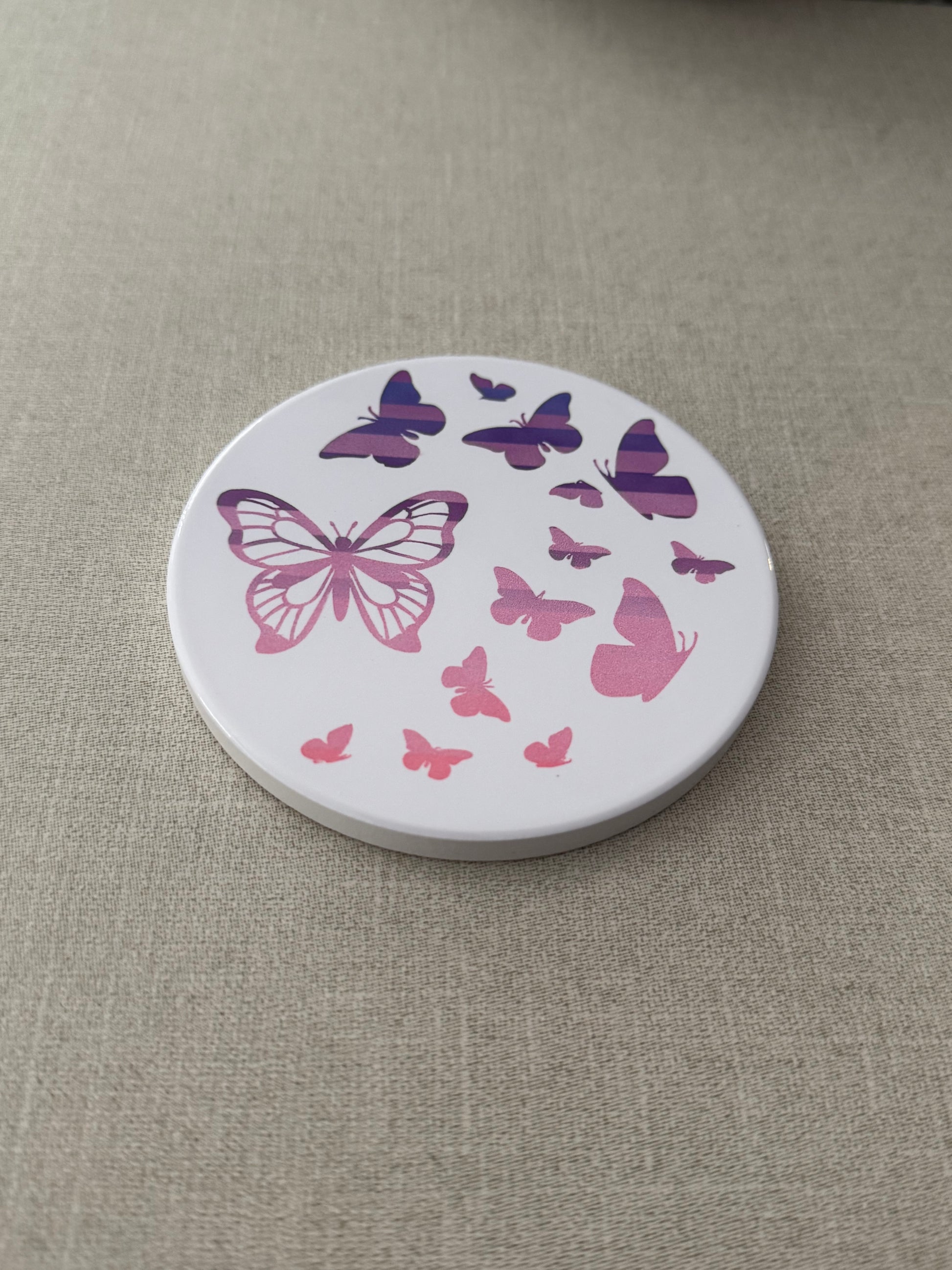 Round ceramic whit coaster designed with pink and purple butterflies.