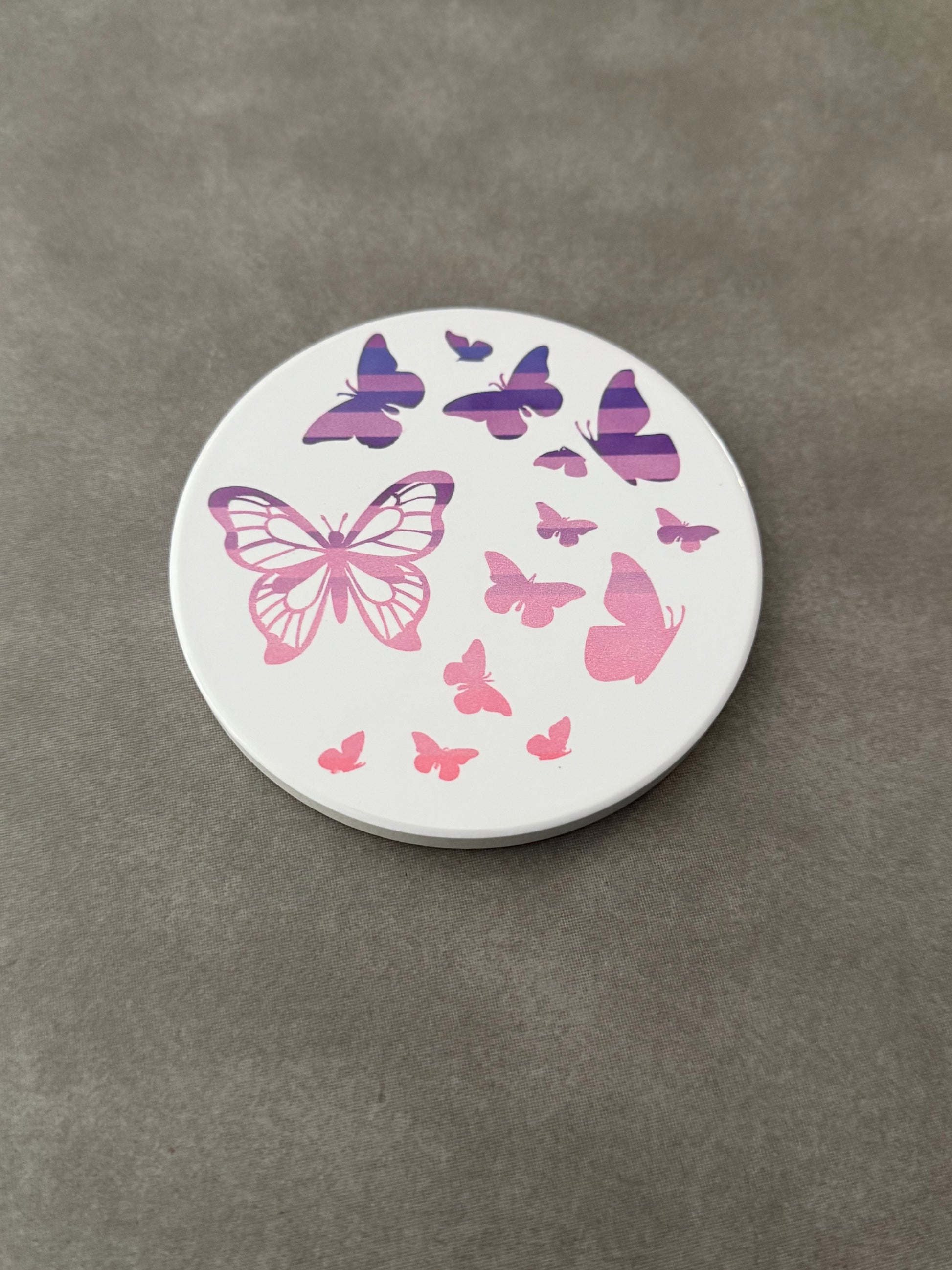 Round ceramic whit coaster designed with pink and purple butterflies.