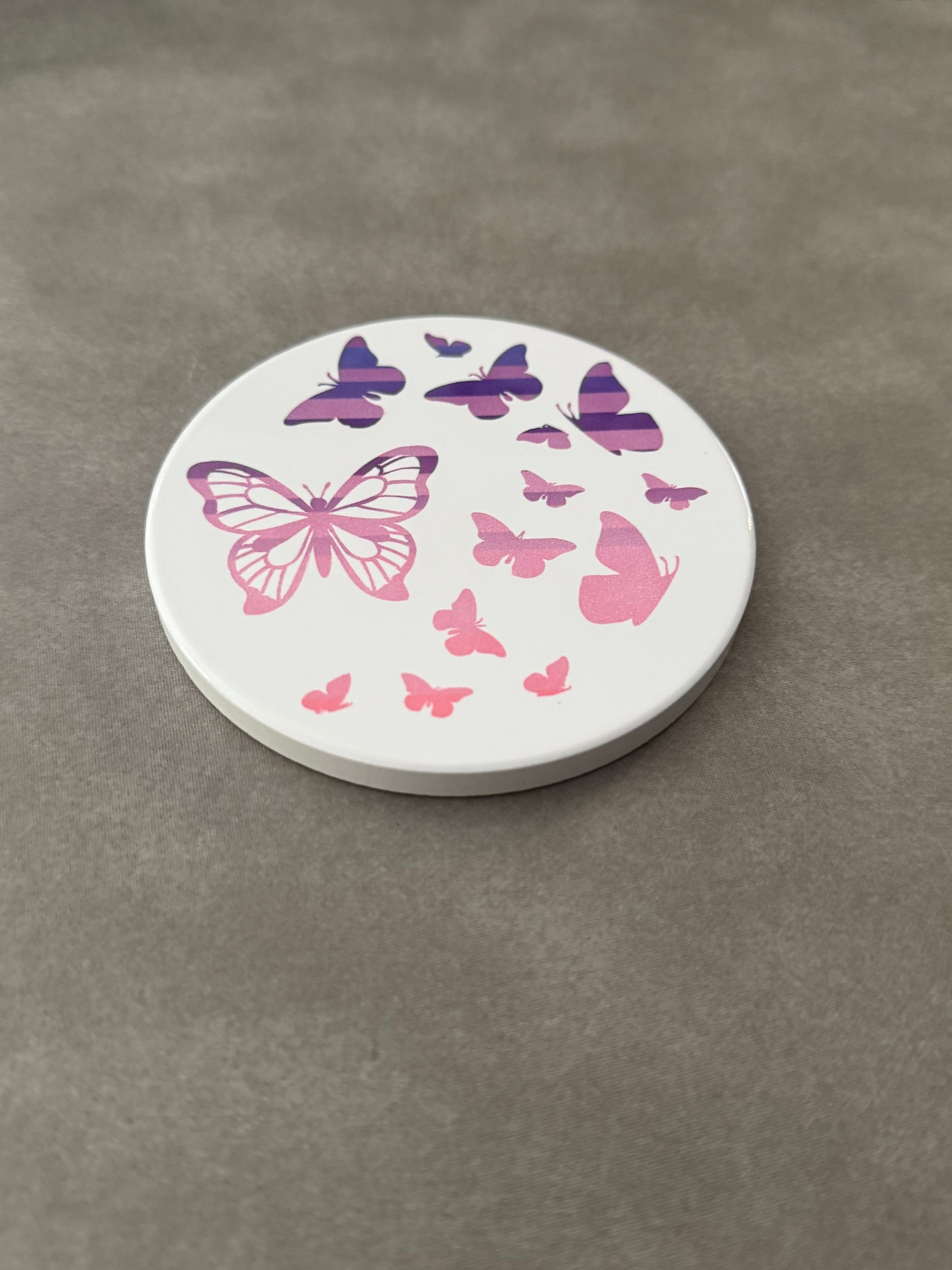 Round ceramic whit coaster designed with pink and purple butterflies.