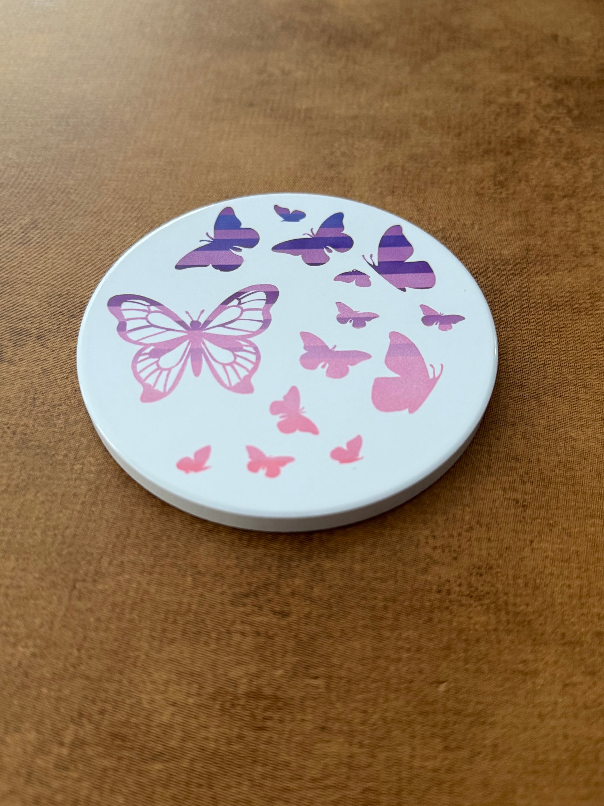 Round ceramic whit coaster designed with pink and purple butterflies.