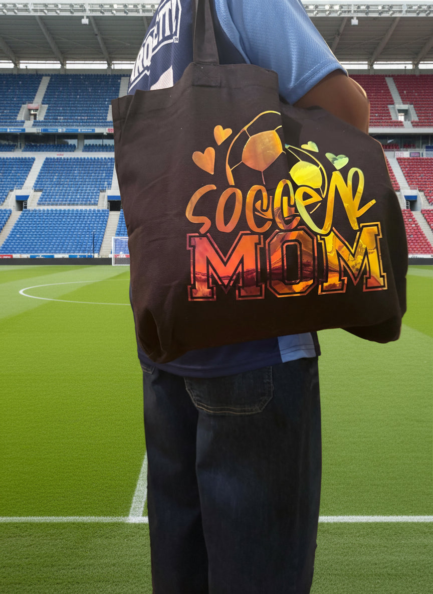 Person carrying a black tote bag with holographic soccer ball and soccer mom design, Roxzell