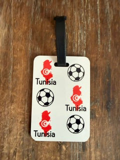 Tunisia soccer luggage tag with black strap on wooden surface. Roxzell