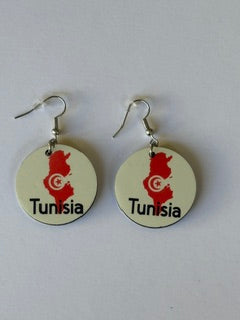 Pair of circular earrings featuring Tunisia’s map outline in red with a white crescent and star emblem and the word “Tunisia” printed below, displayed on a white surface. Roxzell