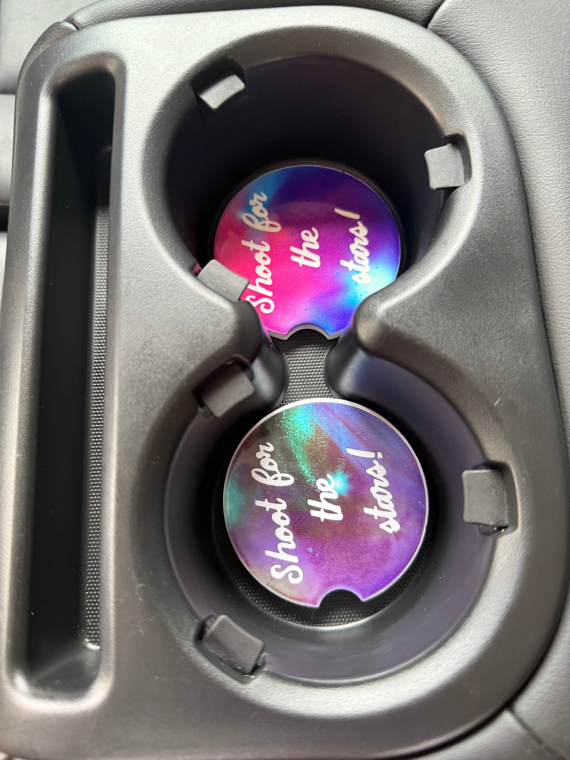 Two colorful car cup coasters with 'Shot the Stars' design inside a vehicle's cup holders Roxzell