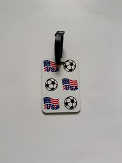 White luggage tag with USA flags and soccer balls. Roxzell