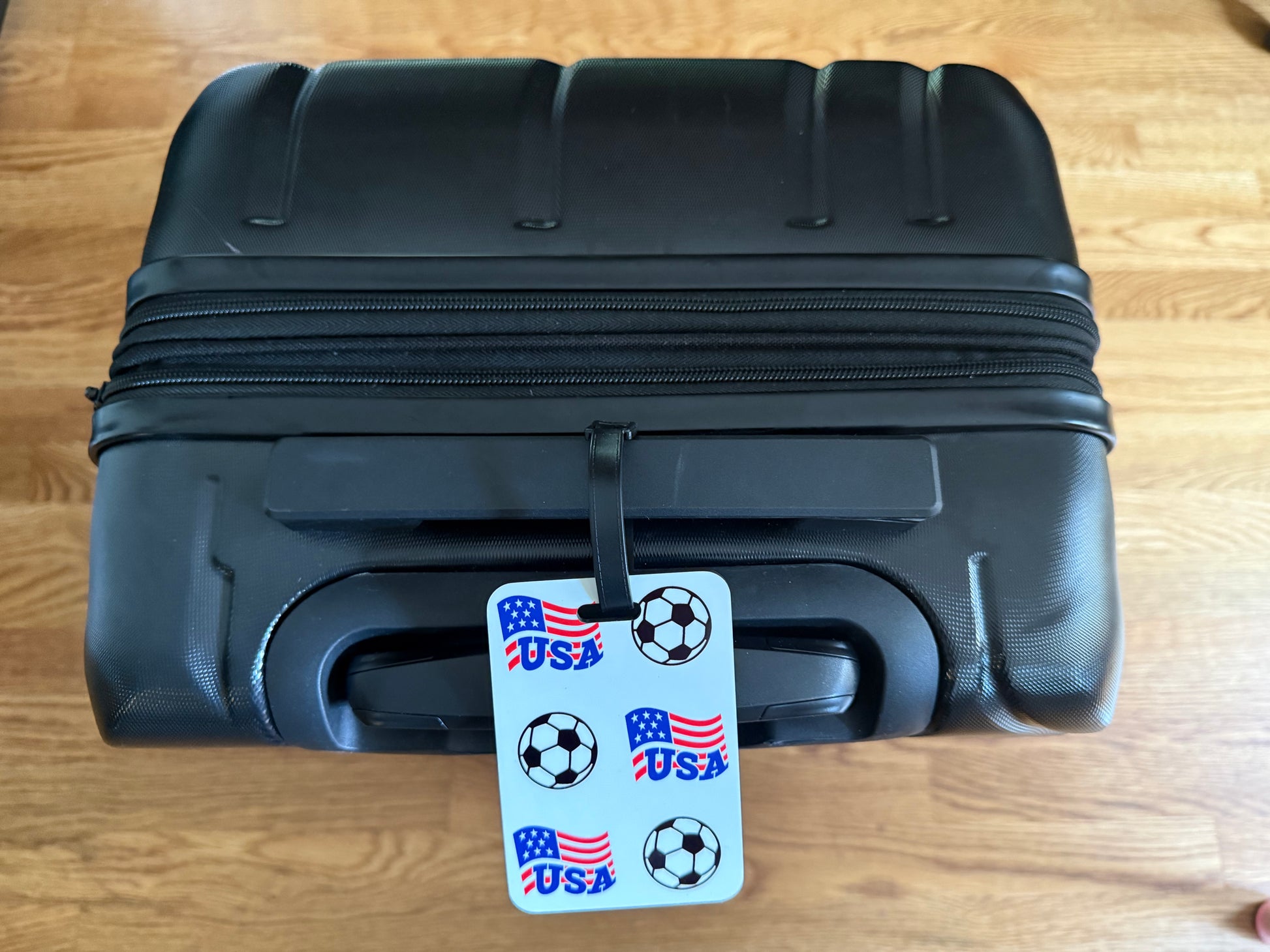 American flag‑inspired travel tag featuring football icons on a black suitcase. Roxzell