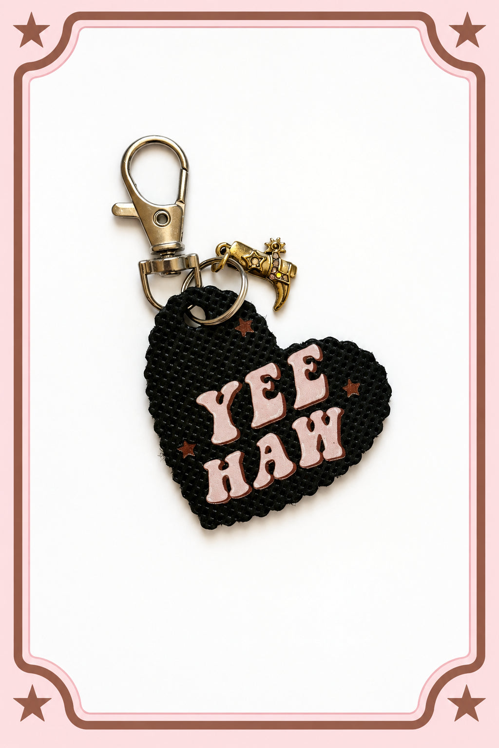 A black heart-shaped woven keychain with the words 'YEE HAW' in light pink letters and small pink star accents, attached to a silver lobster clasp and a small gold-tone horse charm, shown on a plain light background. Roxzell