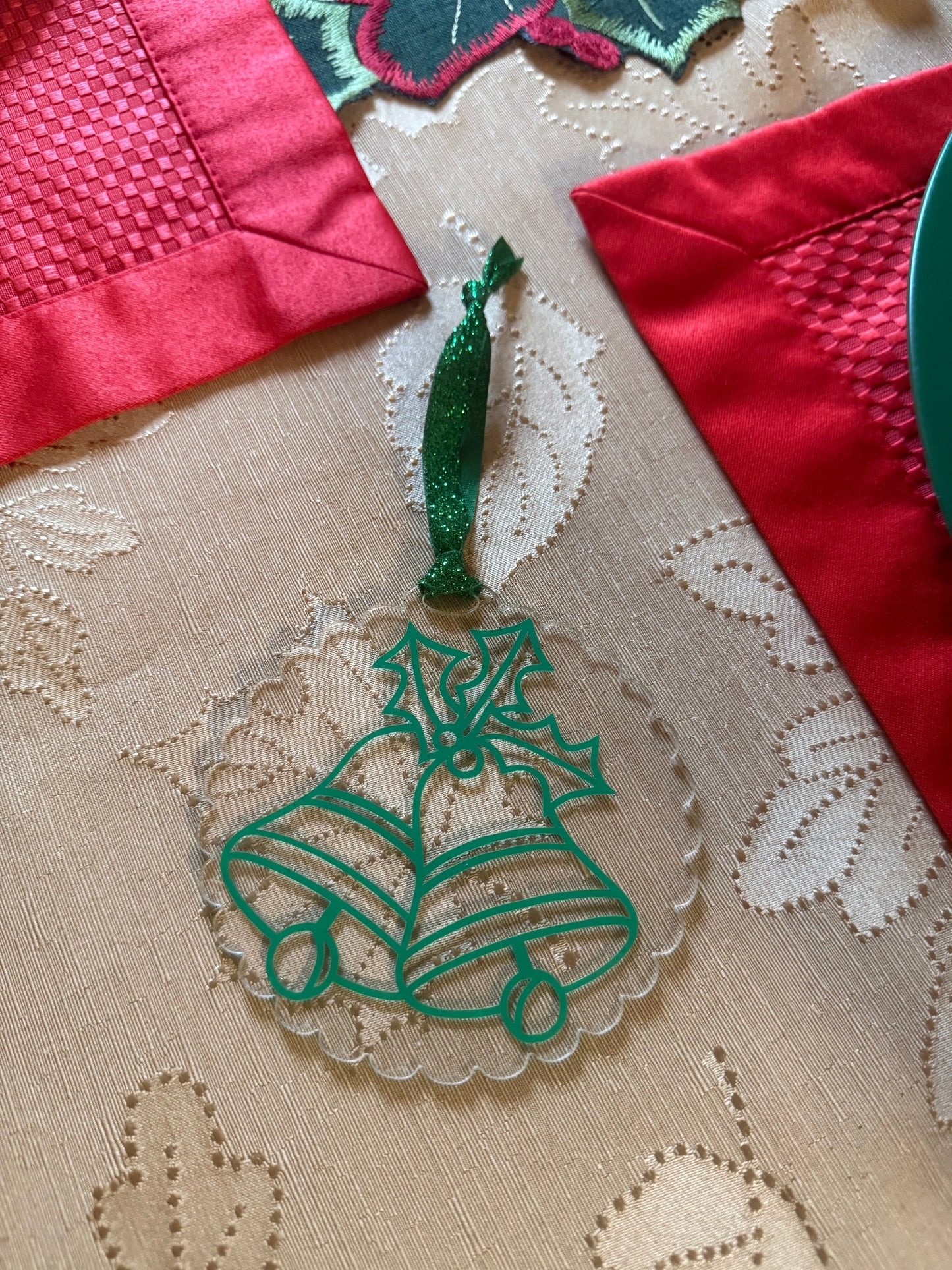 Traditional green bells and holly Christmas ornament displayed on a gold tablecloth with red placemats. Roxzell