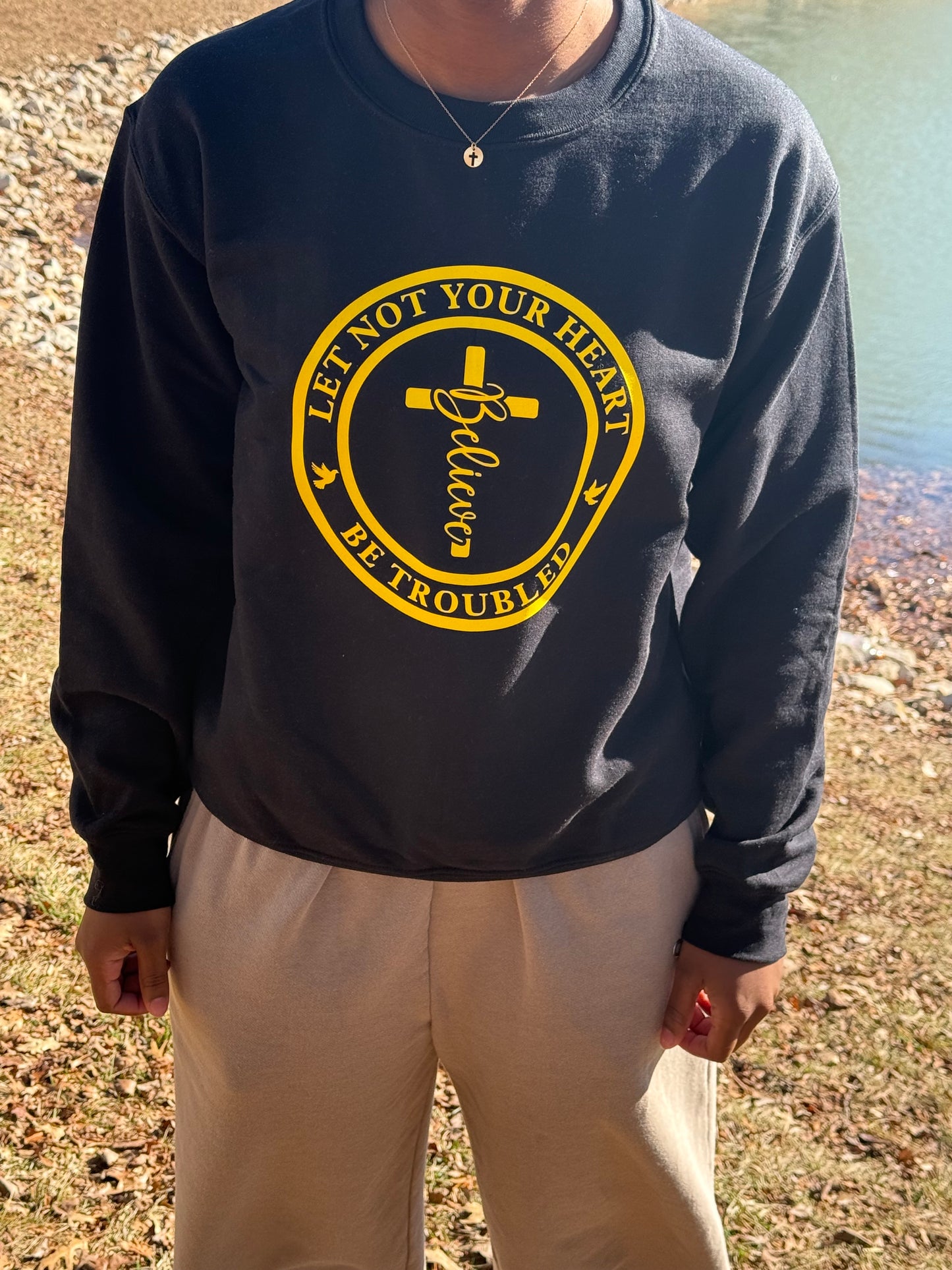 Person wearing a yellow circular graphic with cross, “Believe,” and dove icons, Roxzell