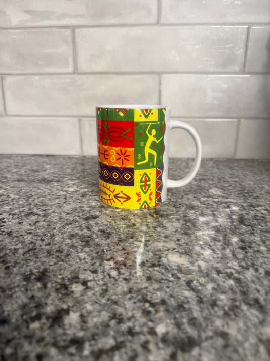 Ceramic mug with vibrant tribal‑inspired patchwork design sitting on a granite countertop. Roxzell
