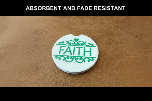 Round white car coaster with green flourishes and vertical FAITH text in center on a brown surface with black border and words "ABSORBENT AND FADE RESISTANT" on the top border.