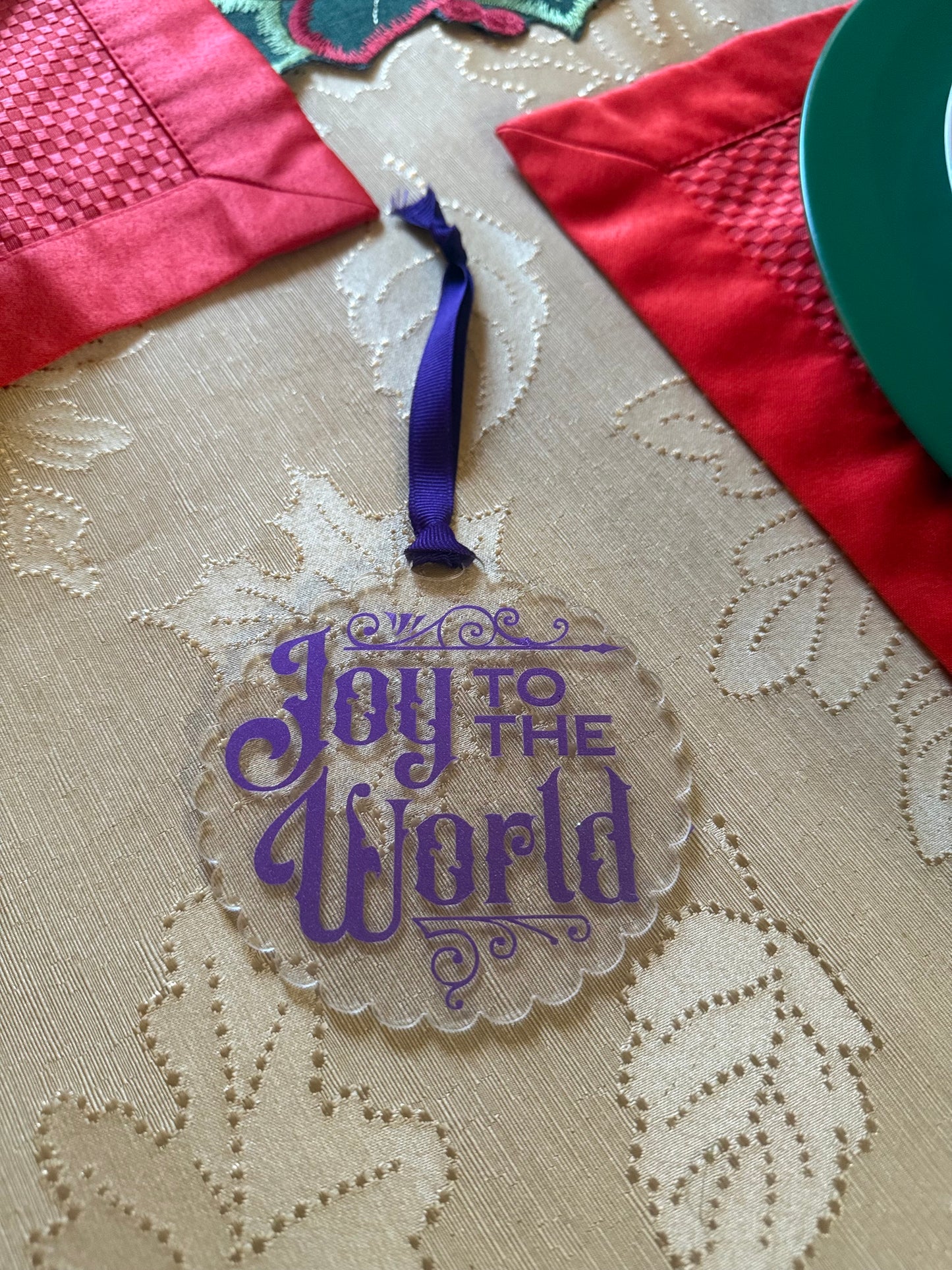 Transparent holiday ornament featuring elegant purple script “Joy to the World” with decorative flourishes, Roxzell