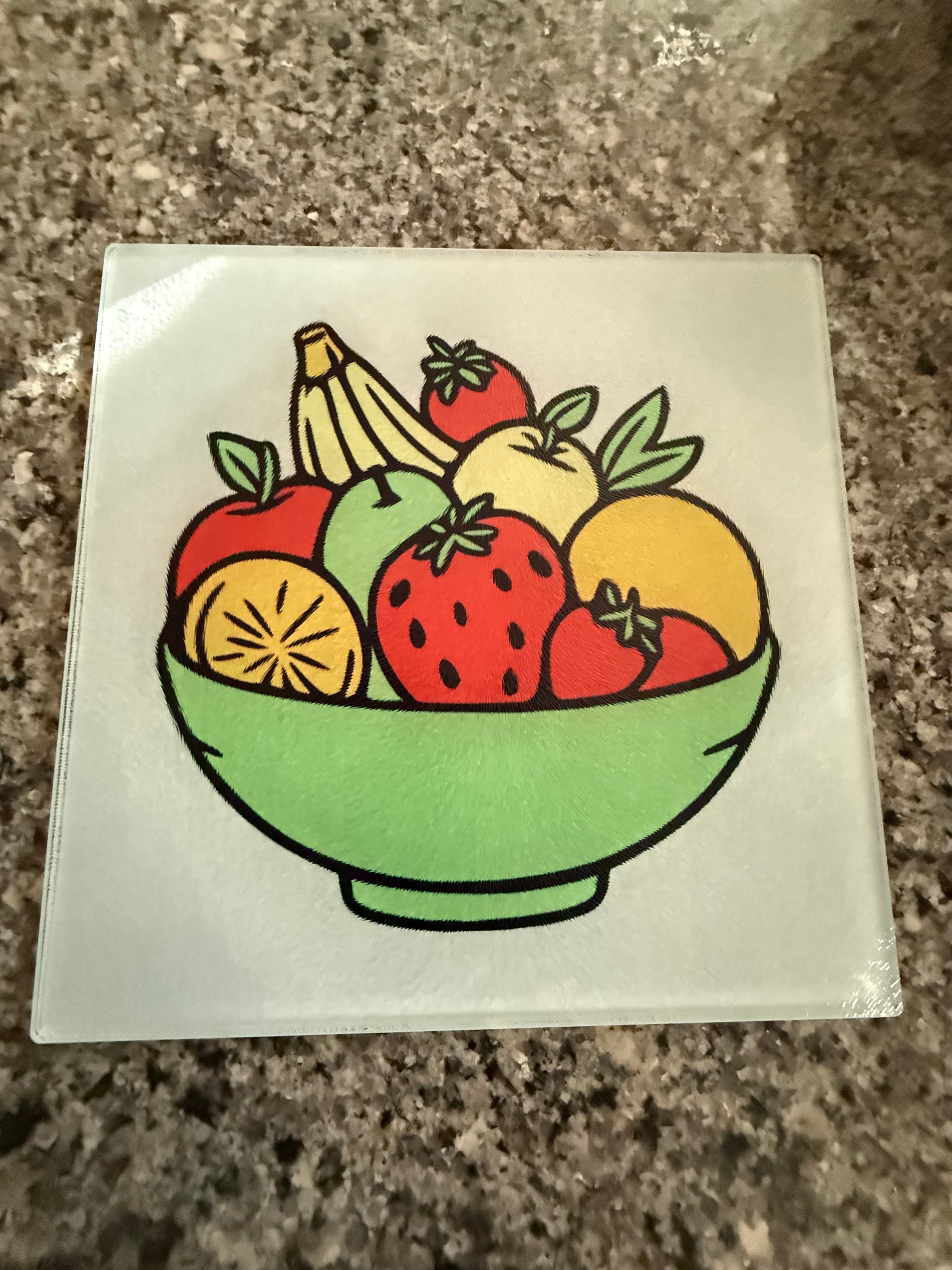 Glass cutting board with colorful fruit bowl design displayed on a kitchen counter, Roxzell