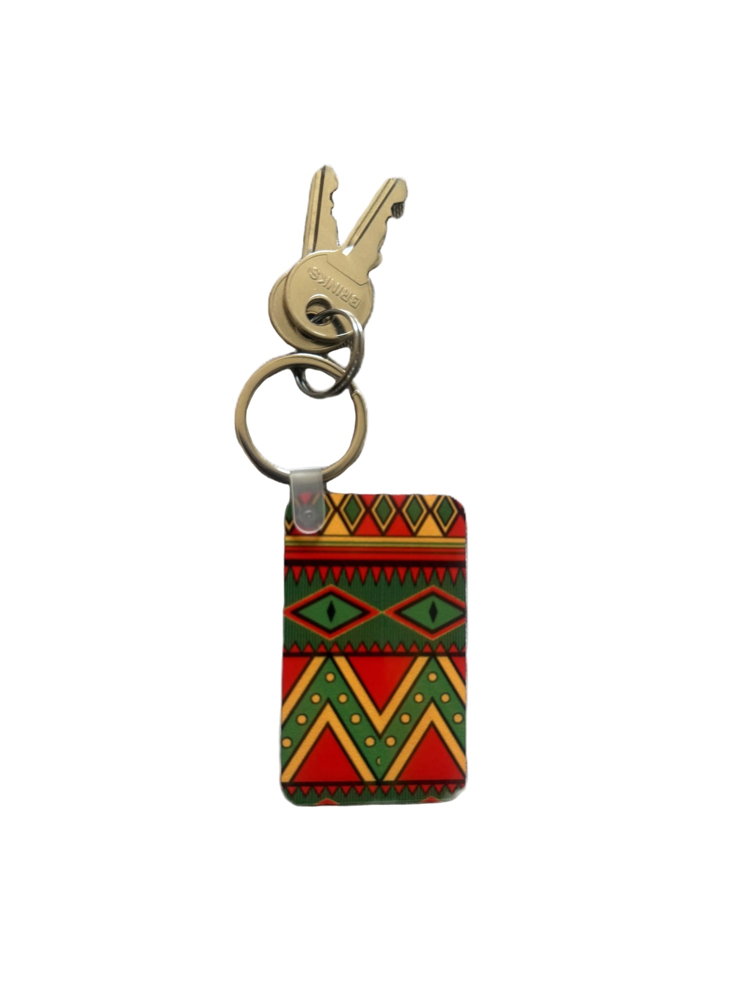 Colorful geometric keychain with red, green, yellow, and black pattern attached to brass keys. Roxzell