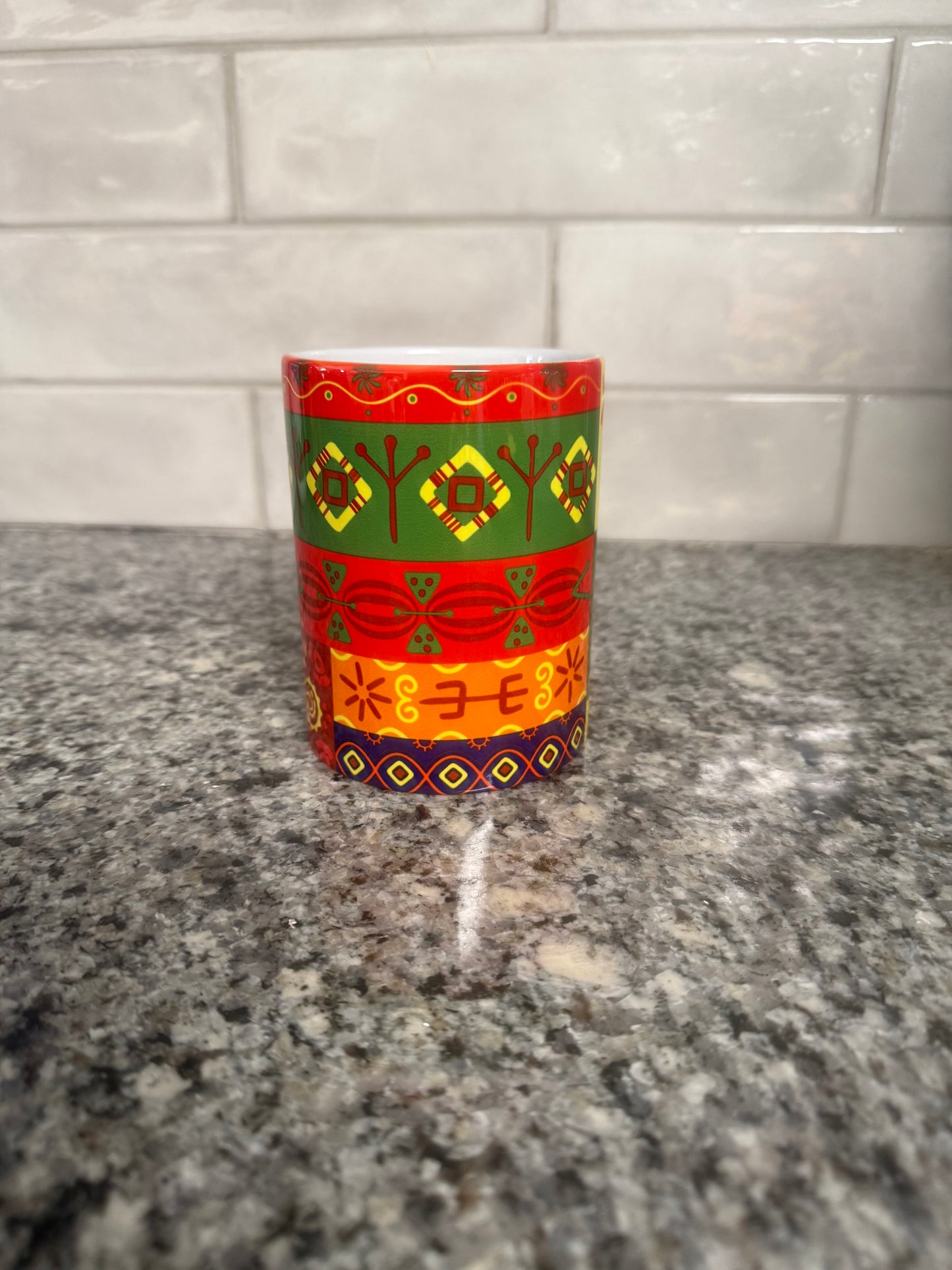 Mug featuring horizontal bands of colorful geometric and floral‑inspired motifs on a granite surface. Roxzell
