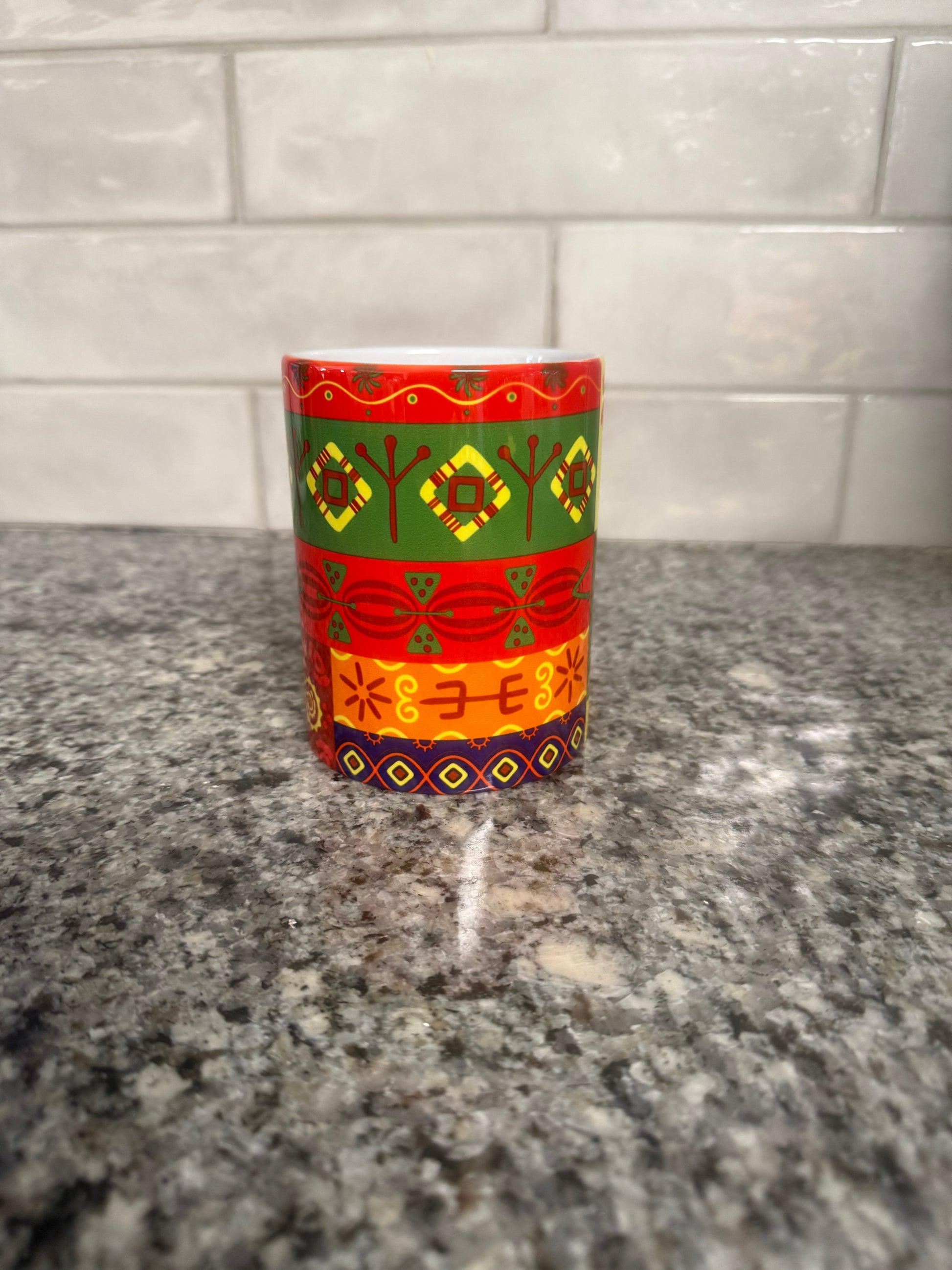 Mug featuring horizontal bands of colorful geometric and floral‑inspired motifs on a granite surface. Roxzell