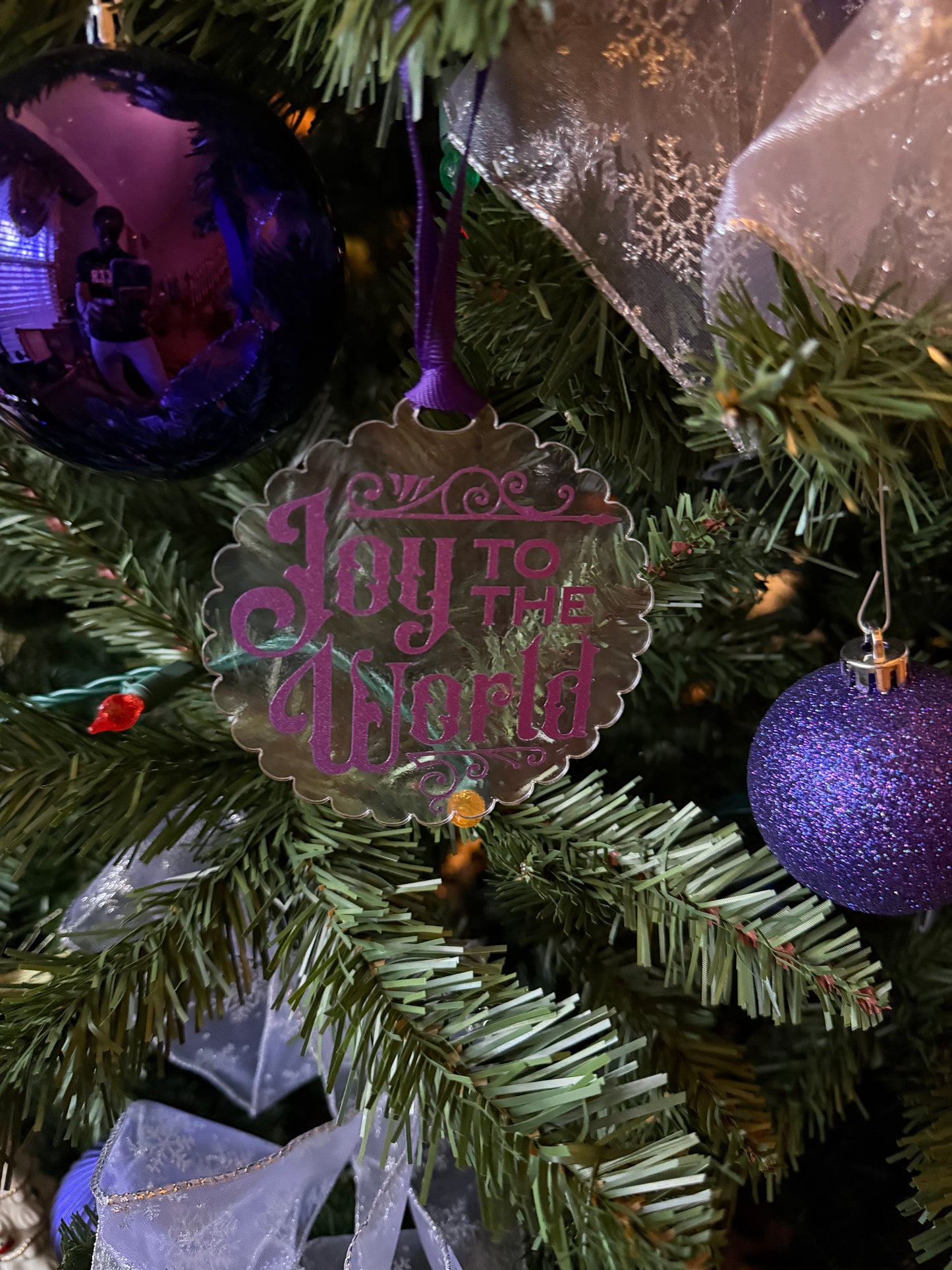 Acrylic Christmas ornament with purple Joy to the World text hanging on a Christmas tree, Roxzell