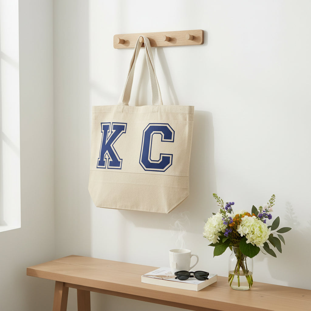 KC canvas tote bag hanging on the wall above a decorated table, Roxzell