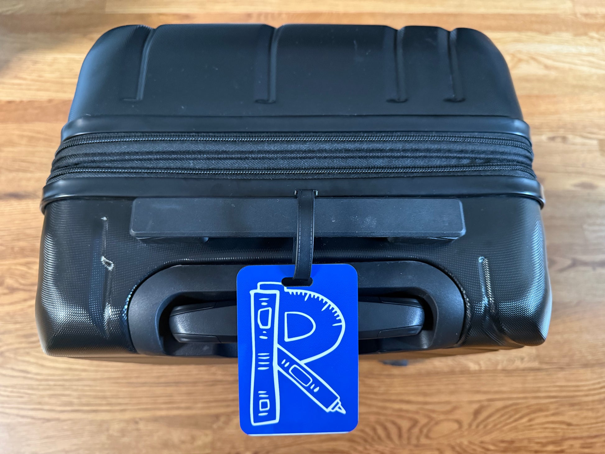 Academic-themed tag clipped to a black carryon bag, Roxzell
