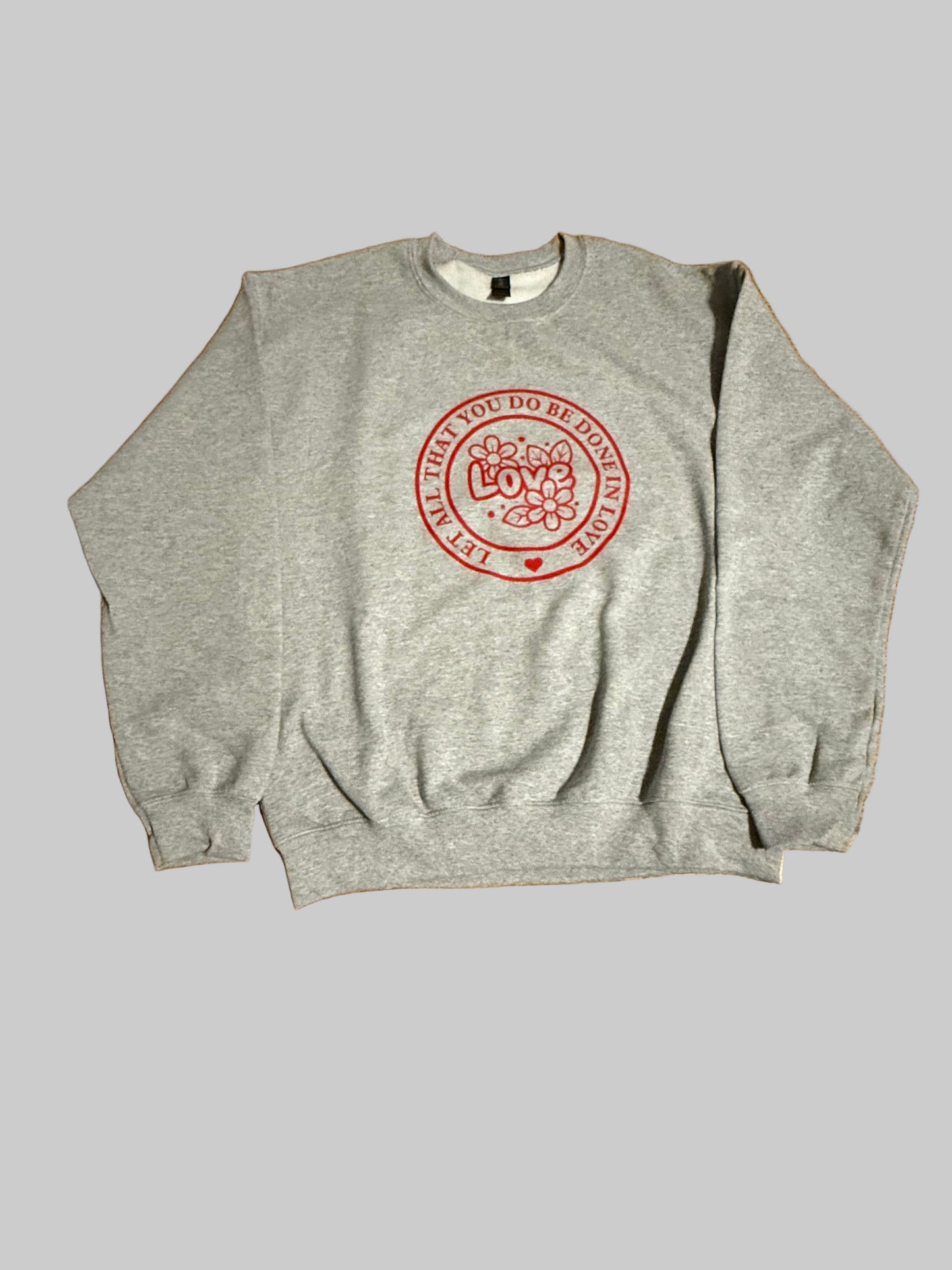 Gray sweatshirt with "Let All That You Do Be Done in Love" saying in a red circle.  The word "Love" and flowers in the center of the circle, Roxzell