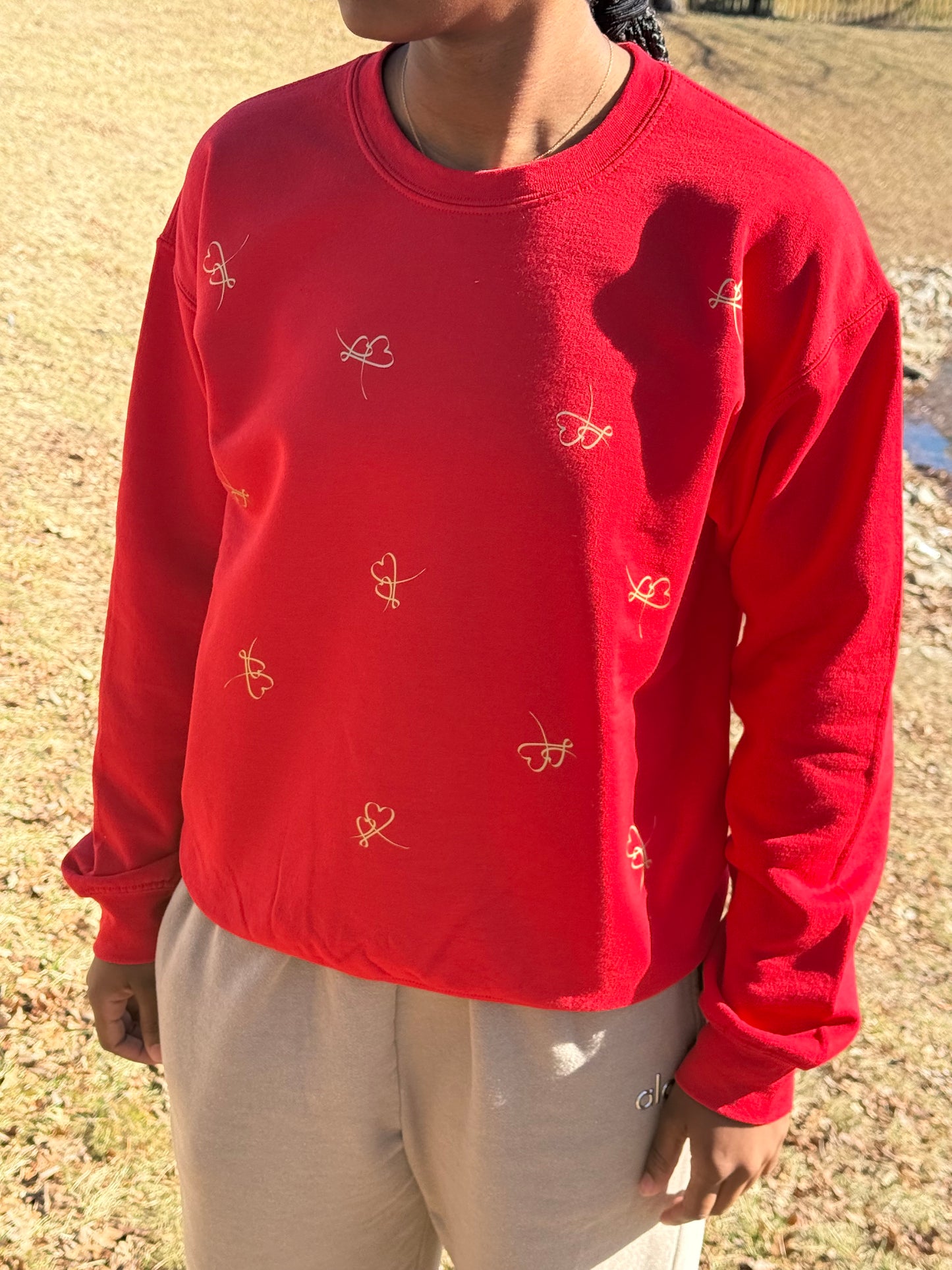 Cozy red sweatshirt featuring whimsical loop‑style heart embroidery, Roxzell