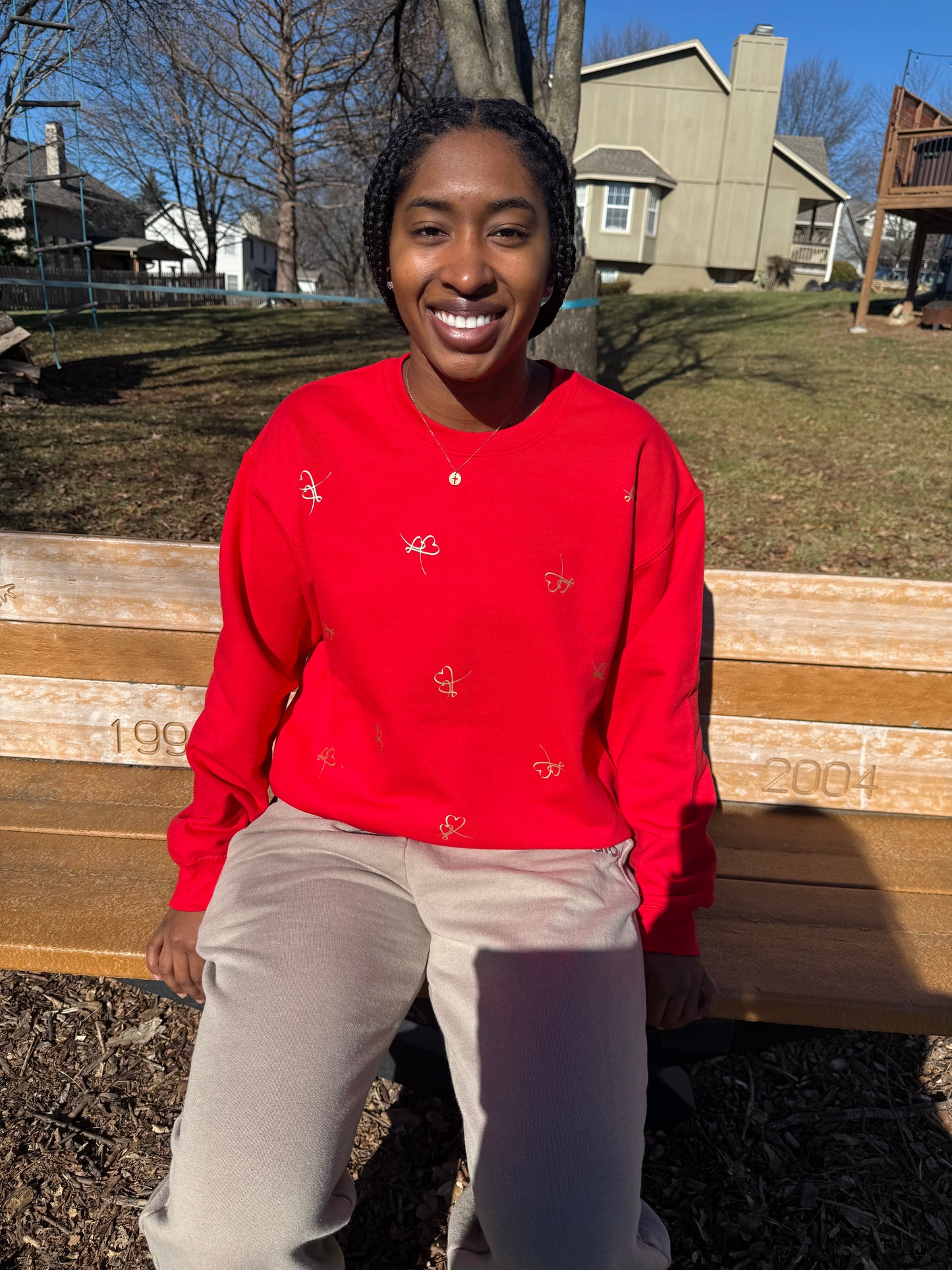 Person wearing a red sweatshirt with embroidered hearts for Valentine’s Day fashion, Roxzell