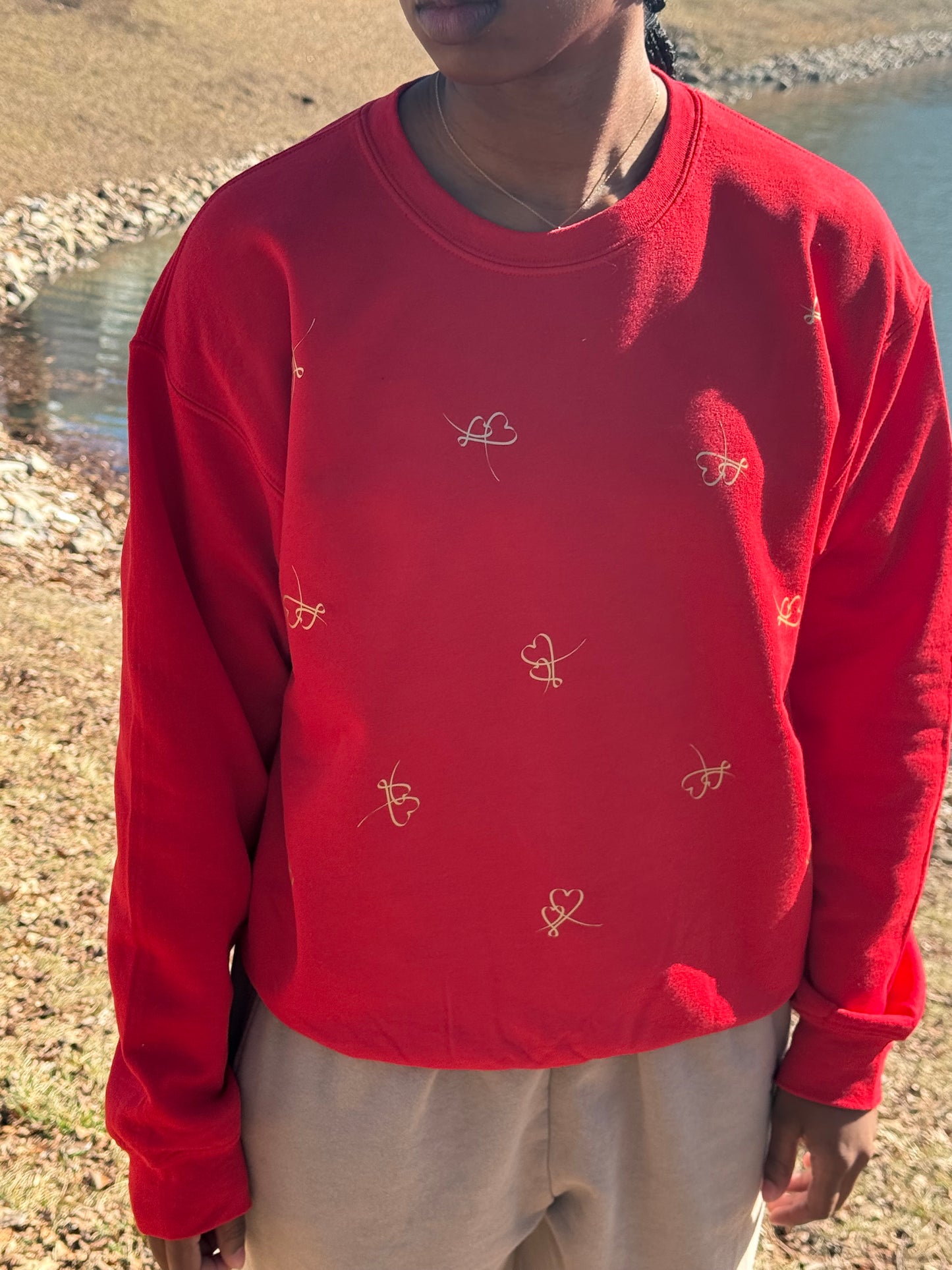 Romantic red pullover with decorative heart details worn in a grassy outdoor setting, Roxzell