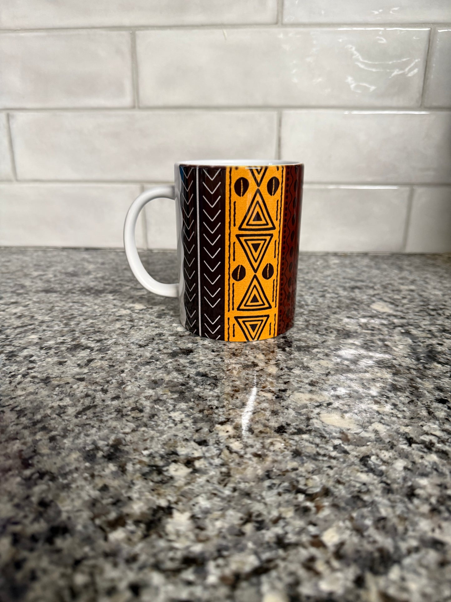 Colorful ceramic mug showing bold geometric motifs in warm earth tones.