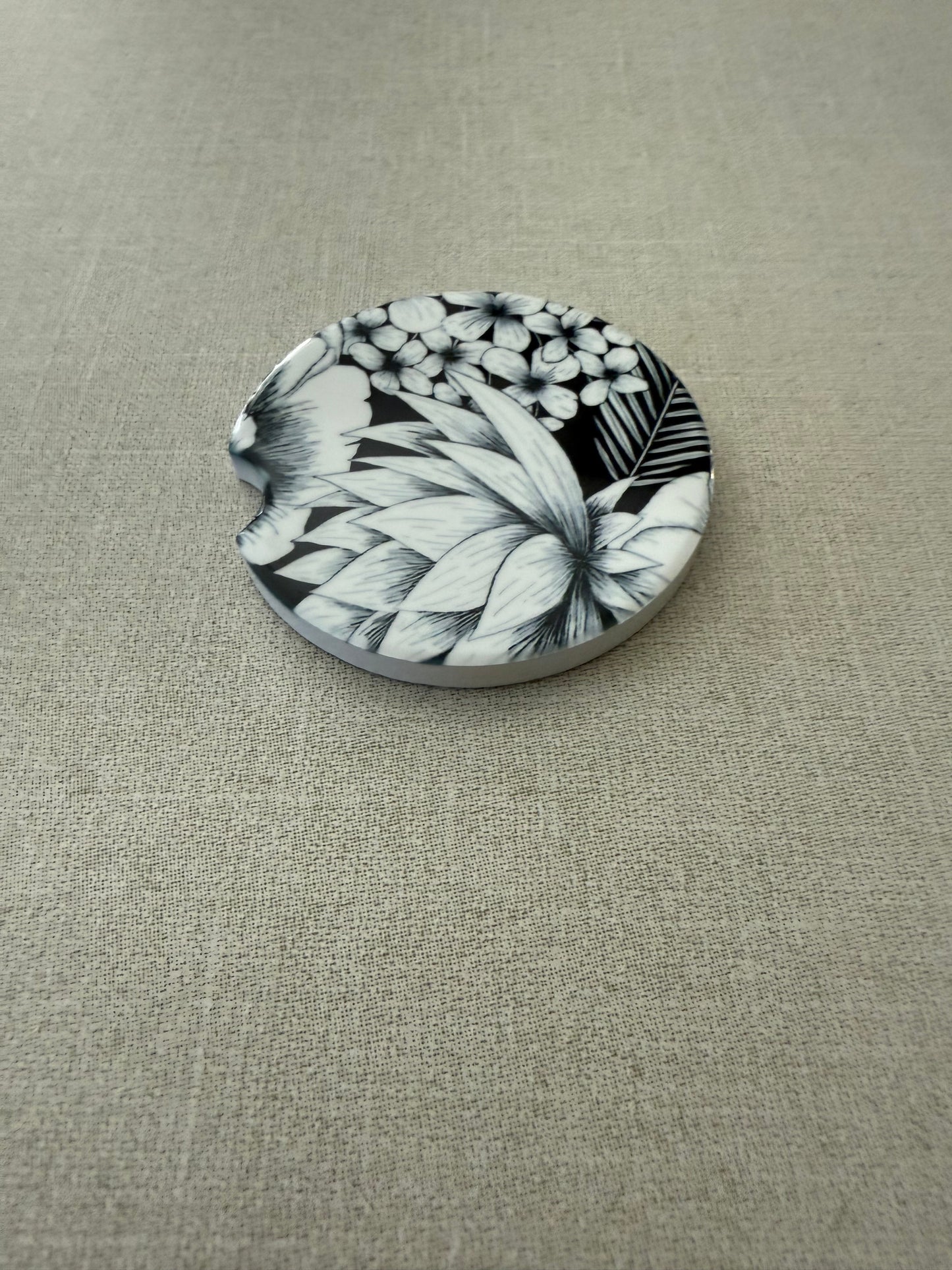 Vintage-inspired car coaster with black and white floral motif and notch detail on light gray background, Roxzell