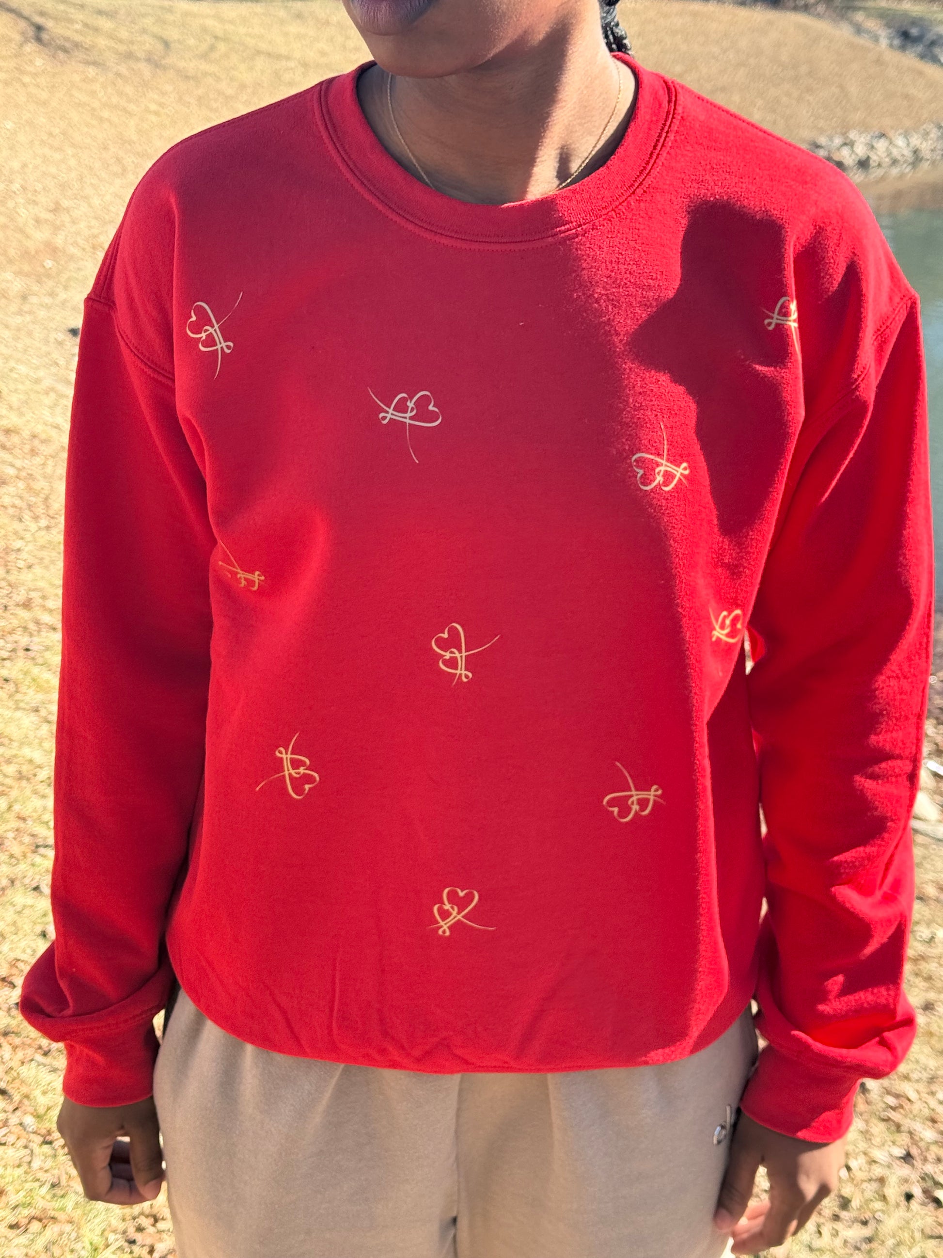 Red heart‑embroidered sweatshirt styled with neutral pants in natural light, Roxzell